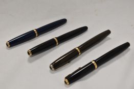 Four Parker Duofold button fill fountain pens in olive green, black and blue all having Parker nibs.