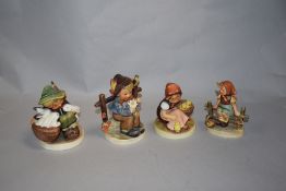 Four Goebel figurines, including boy with rabbits and girl with chicks.