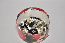 An assorted collection of costume jewellery, to include a circular ebonised brooch with white