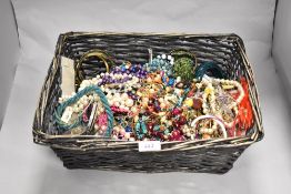 A basket of miscellaneous costume jewellery, bangles, necklaces, and earrings