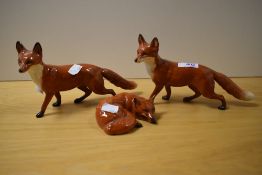 Three Beswick Pottery fox studies, two standing and one laid down.