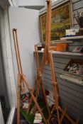 A group of three free standing folding artist's easels, and a pine desk easel