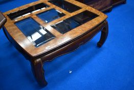 An Oriental coffee table having smoked glass panels to top, approx. 97 x 97cm