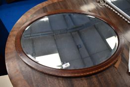 An Edwardian mahogany and inlaid oval wall mirror
