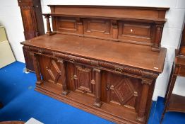 A Victorian oak sideboard having panelled ledge back carved frieze drawers with Jacobean style