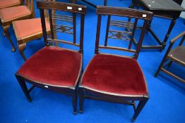 A pair of Victorian mahogany dining chairs having red dralon drop in seats