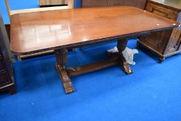 An early 20th Century oak dining table having carved frame cup and cover supports with vine