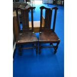 A pair of period oak solid seat dining chairs harving carved decoration