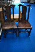 A pair of period oak solid seat dining chairs harving carved decoration