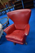 A vintage revolving easy chair having red vinyl upholstery