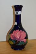 A William Moorcroft tube lined bottle vase, in the Pink Magnolia design, on blue ground, measuring