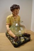 An early 20th Century kitsch advertising figure, modelled as a seated boy, a glass storage jar