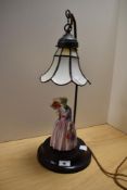 A continental porcelain figural table lamp, with a Tiffany style glass shade, measuring 51cm