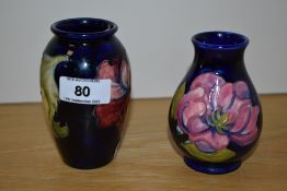 Two William Moorcroft cobalt blue bud vases, to include a hibiscus design vase, the largest measures