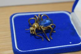 A 1930s Art Deco brooch, in the form of a bug, the yellow metal body surrounding a blue glass