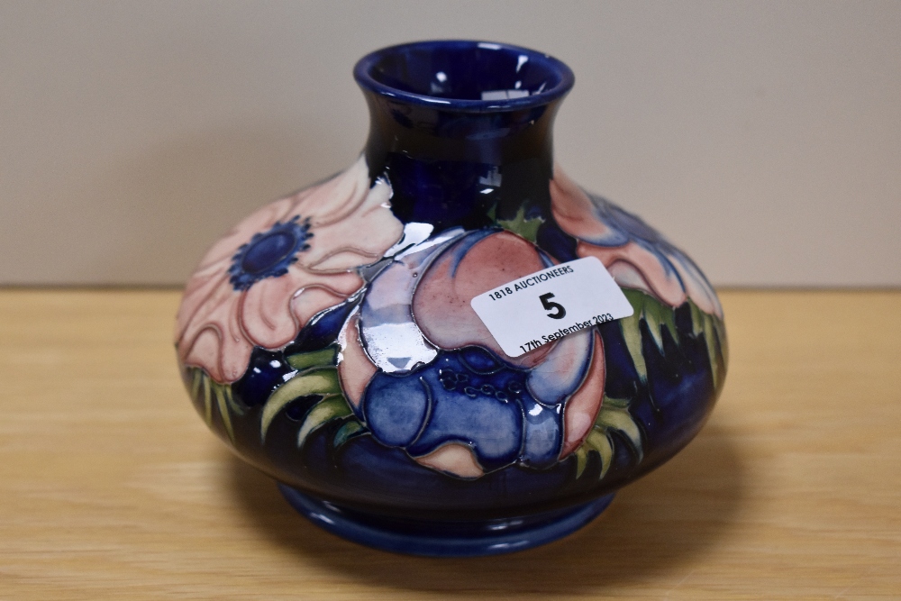 A William Moorcroft tube lined anemone vase of squat form, on blue ground, measuring 11.5cm tall