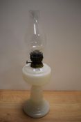 A vintage milk glass oil lamp with chimney.