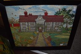 A vintage tapestry depicting country house with garden, framed and glazed.