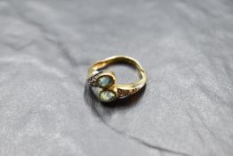 An 18ct gold open crossover ring having oval blue topaz to terminals and white stones to
