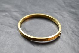 A 9ct gold filled hinged bangle having engine turned decoration and concealed clasp, internal