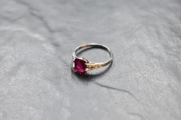 A baguette cut ruby ring, approx 1ct, in a claw set mount, having diamond set split shoulders on a