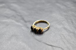 A cabochon onyx trio ring interspersed by cubic zirconias on a yellow metal loop, no marks but tests