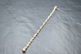 A 9ct white and yellow gold articulated bracelet having 12 white gold lozenge panels, each