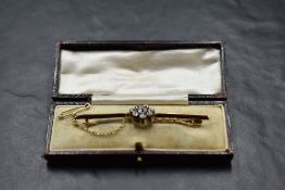 A yellow metal bar brooch with a central diamond daisy cluster, total approx 0.75ct, with safety