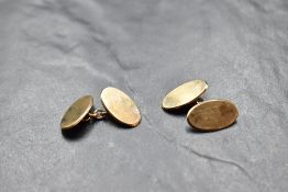A pair of 9ct gold cufflinks of plain oval form having chain connectors, approx 7.3g