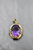 An amethyst pendant of oval form in a decorative yellow metal open mount, no marks or chain