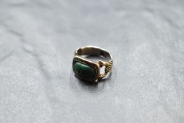 A Victorian yellow metal ring having a malachite panel to moulded scallop shell shoulders on a