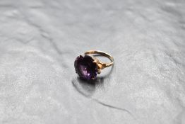 An oversized Alexandrite solitaire ring in a 4 claw basket mount to decorative shoulders on a yellow