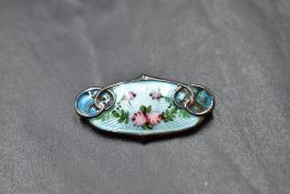 A white metal and enamel brooch stamped sterling having floral decoration