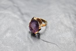 An oval amethyst ring having a claw set stylised mount on a 9ct gold loop, size M & approx 4.7g