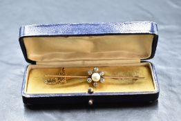 A yellow metal bar brooch having a central pearl and diamond daisy cluster, with six diamonds