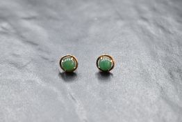 A matched pair of green cabochon stone stud earrings in rose gold mounts stamped 4K