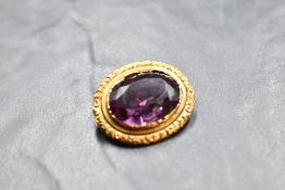 A yellow metal brooch stamped 15ct having a large oval amethyst style stone in a decorative mount,
