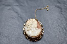 A conch shell cameo brooch depicting a maiden in profile in a 9ct gold decorative mount