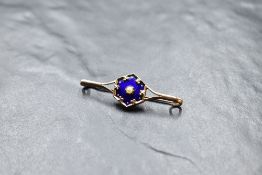 A yellow metal bar brooch having central enamelled plaque with seed pearl decoration, no marks,