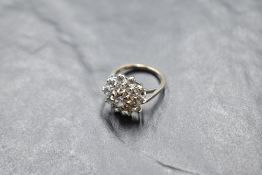 A large white stone triple cluster ring having a stepped claw set basket mount on an 18ct white gold