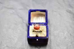 A coral bead ring topped with an inset diamond, approx 0.064ct on a yellow metal loop stamped