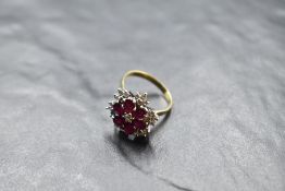 A multi cluster ring having a central diamond surrounded by six oval rubies in petal form within a