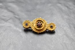 A yellow metal bar brooch stamped 18ct having central ruby and sapphire chip and wire decoration,