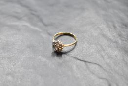A diamond daisy cluster ring, total approx 0.5ct in a raised claw mount to knife blade shoulders