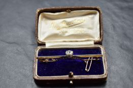 A yellow metal bar brooch with central diamond, approx 1.5ct, with safety chain, approx 5.8g