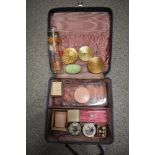 A vanity case containing an assortment of vintage cosmetics, most unused, rollers, perfume, compacts