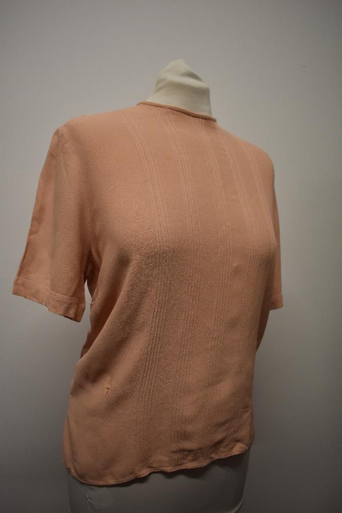 A 1940s blouse in a pale salmon shade, having buttons fastening to reverse and pin tucks to front.