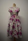 A pretty 1950s floral cotton day dress, commercially made and having full skirt and boat neckline,