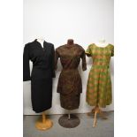A trio of 1950s to 60s dresses, including autumnal toned dress with layered skirt and black wool