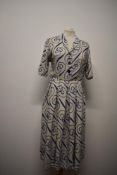 A 1940s linen day dress in white, having blue swirl pattern, button fastening to bodice, side